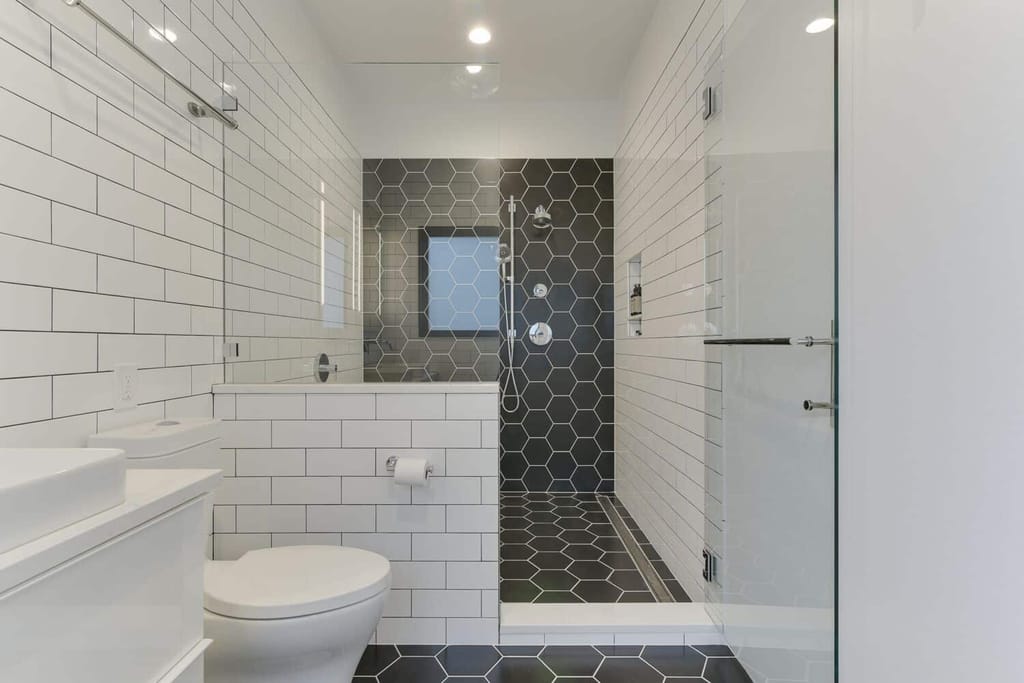 Wet room layout with freestanding tub and shower, featuring hexagon and subway tiles.