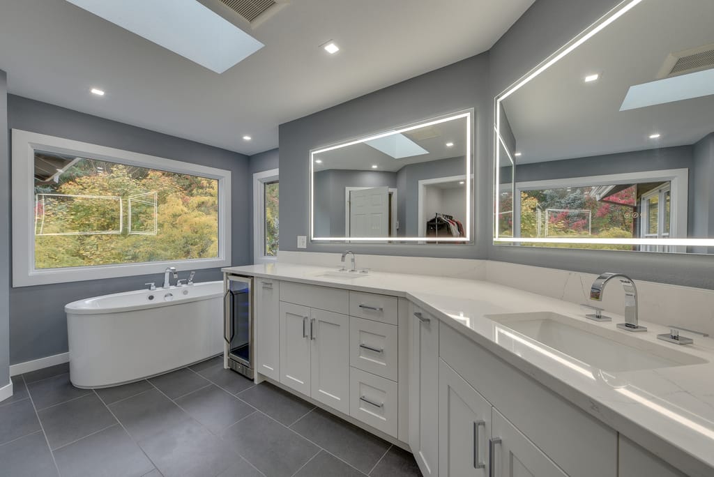 Modern, luxury, minimalist gray tone bathroom with free-standing bathtub and vanity mirrors with integrated lighting