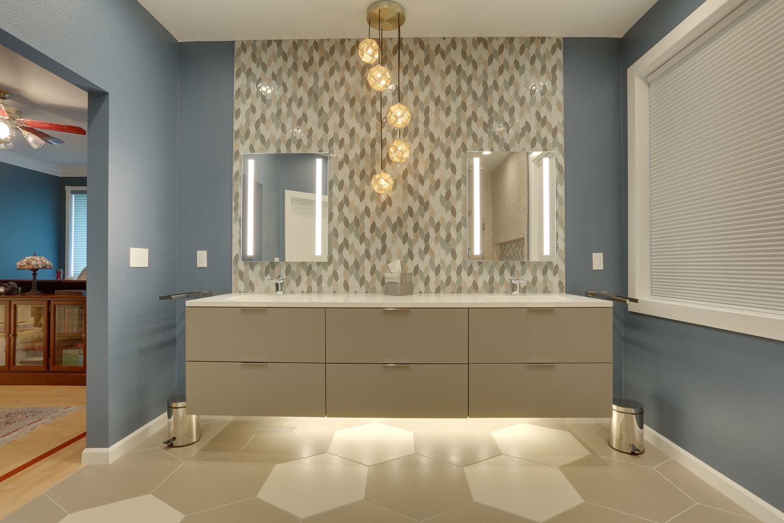 Modern double vanity with pendant lights and decorative tile backsplash.