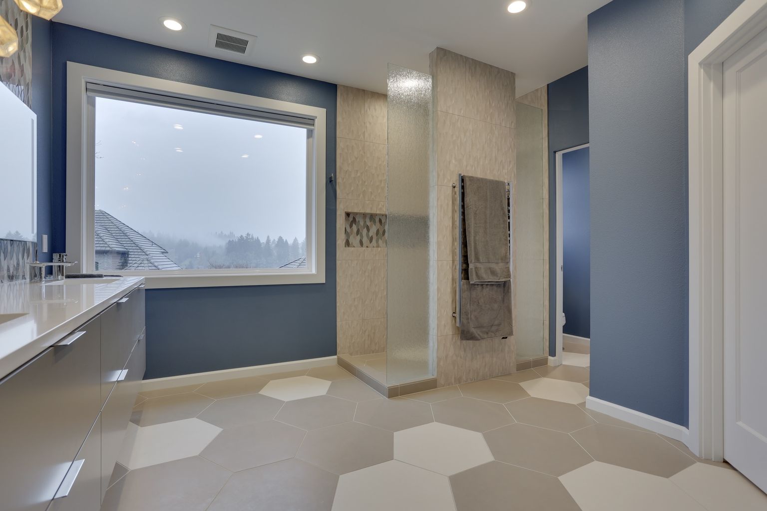 Wide view of spacious bathroom with walk-in shower and large picture window.