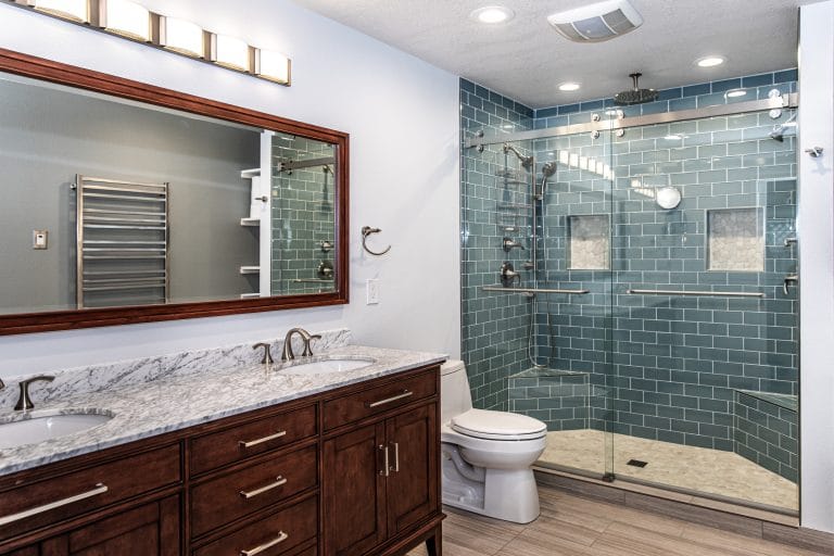 beautiful comtemporary bathroom with blue glass subway tile shower, and chestnut vanity and mirror frame
